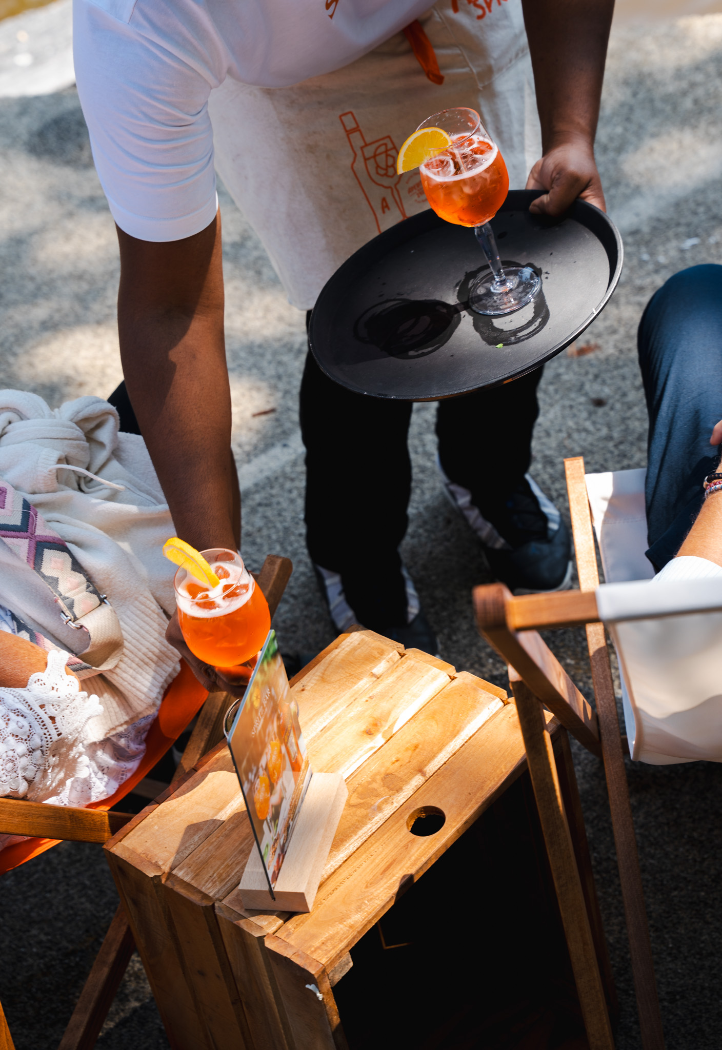 Server carrying Aperol Spritz on tray to guests on the terrace
