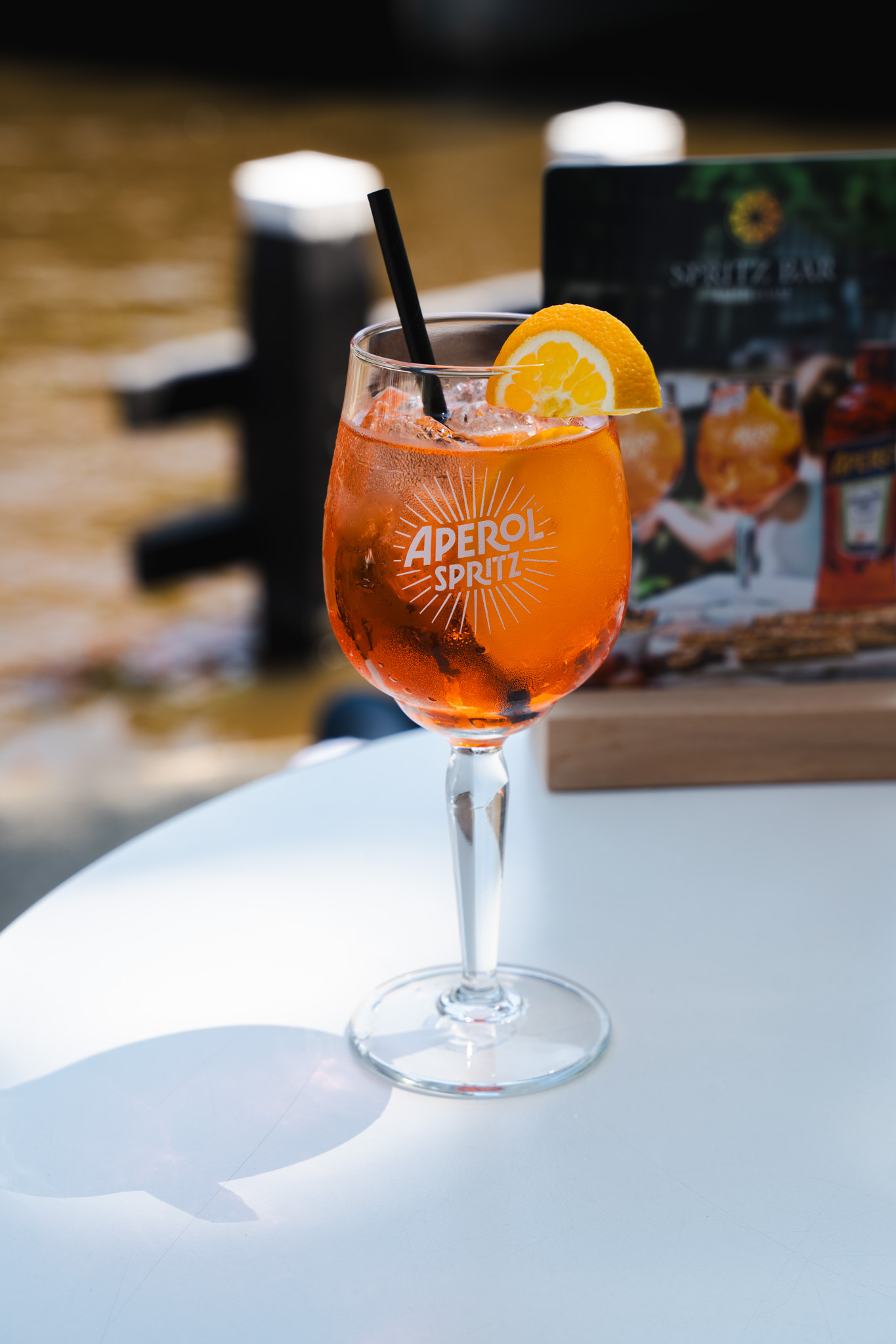Aperol Spritz glass on table with canal in background