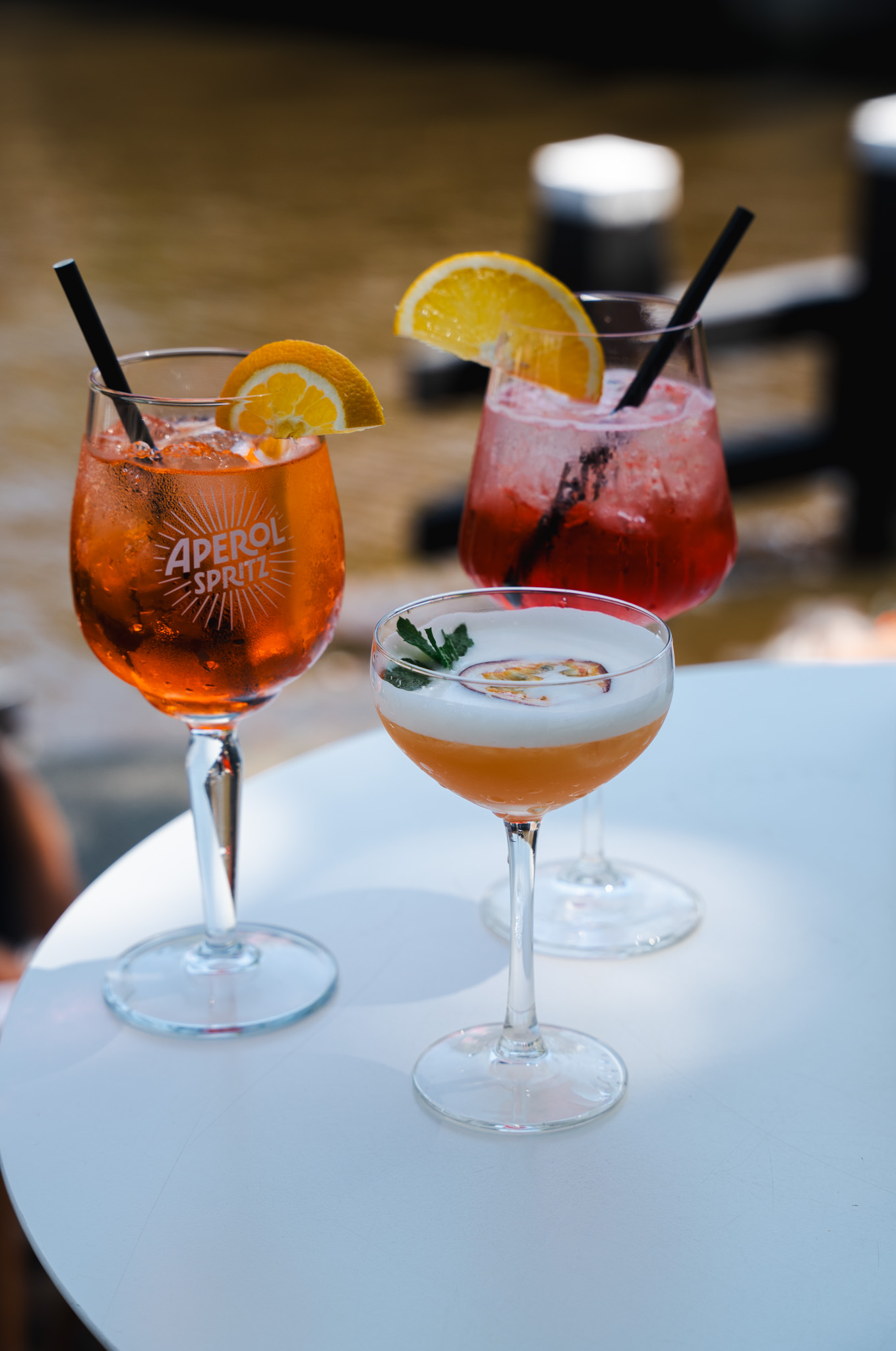 Three different cocktails on a white table by the Amsterdam canal