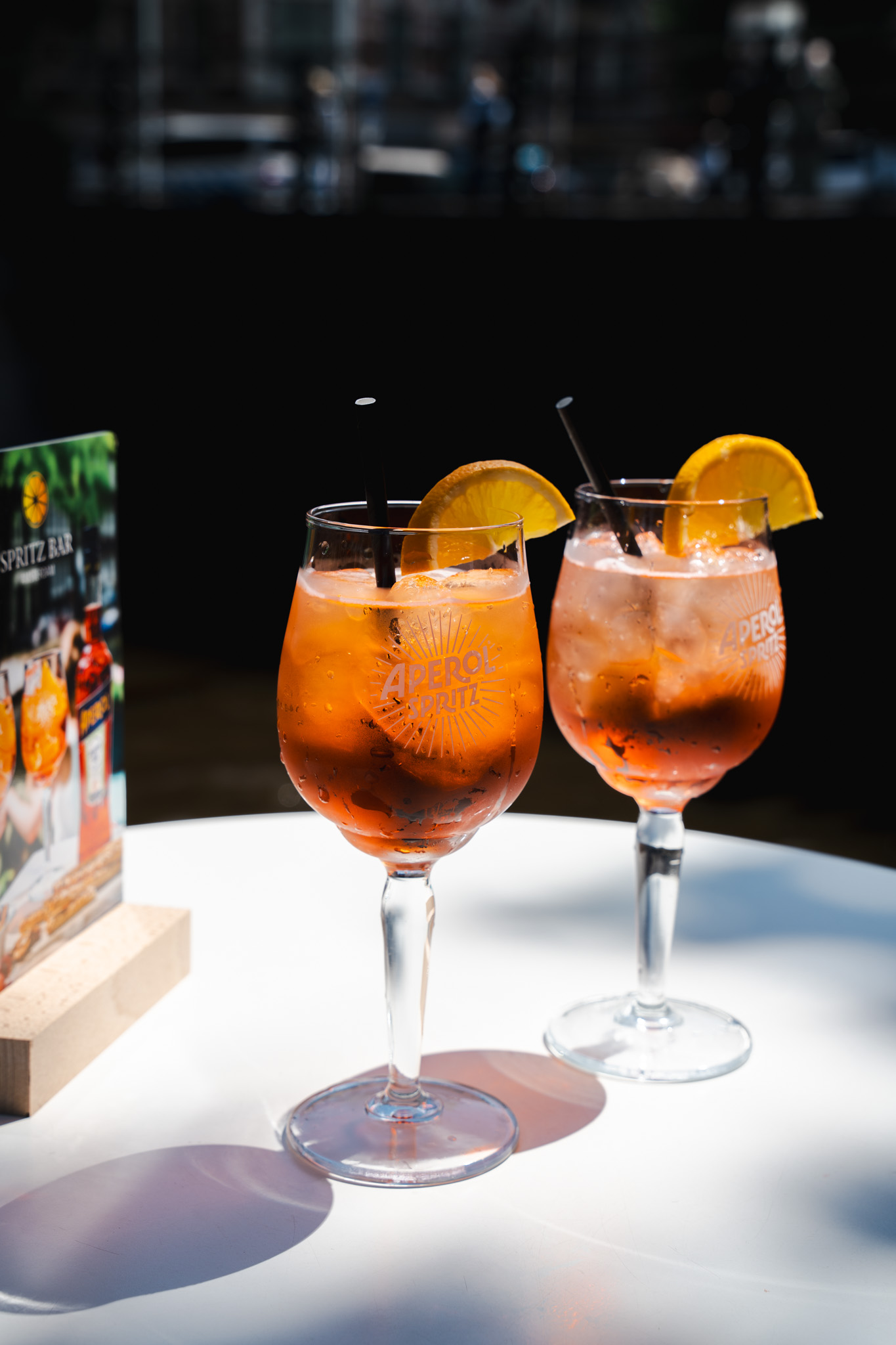 Two Aperol Spritz glasses on white table in the sun